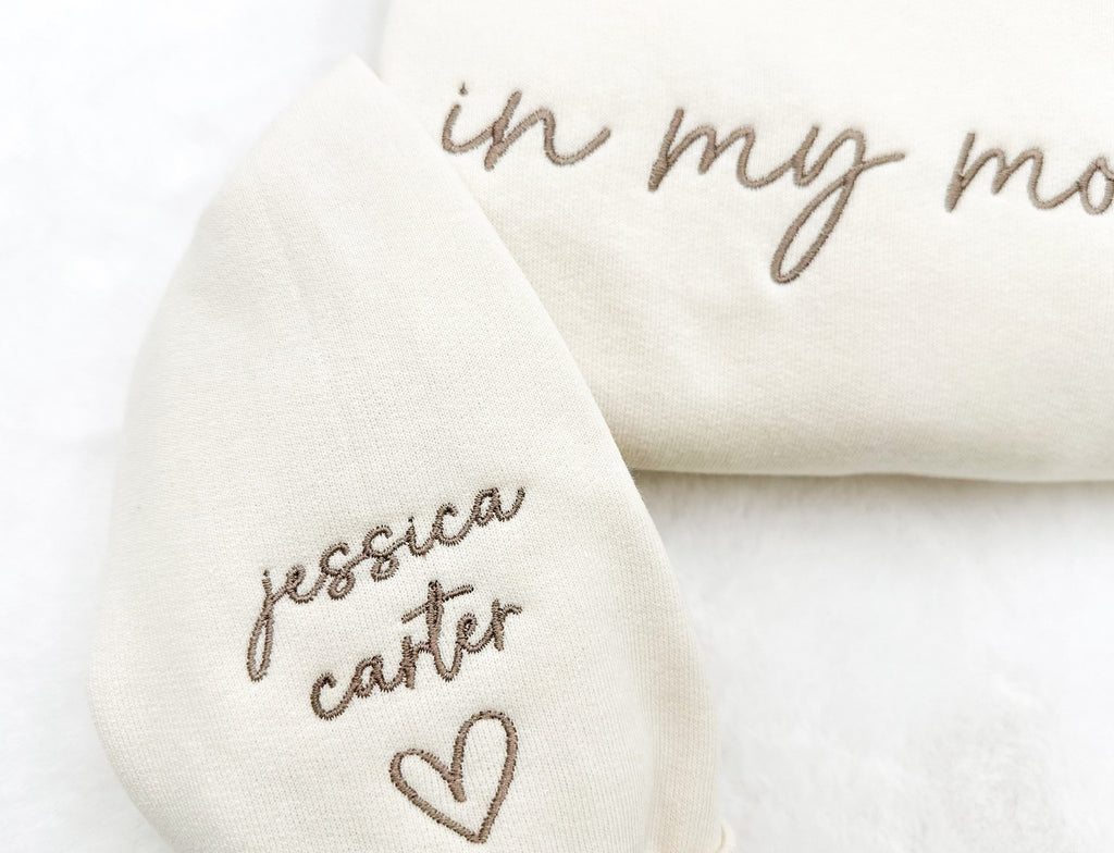 “In My Mom Era embroidered sweatshirt with custom kids’ names on sleeve – neutral cream tone”