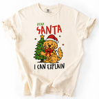 Ivory t-shirt with “Dear Santa I Can Explain” text and cute dog in Santa hat beside Christmas tree