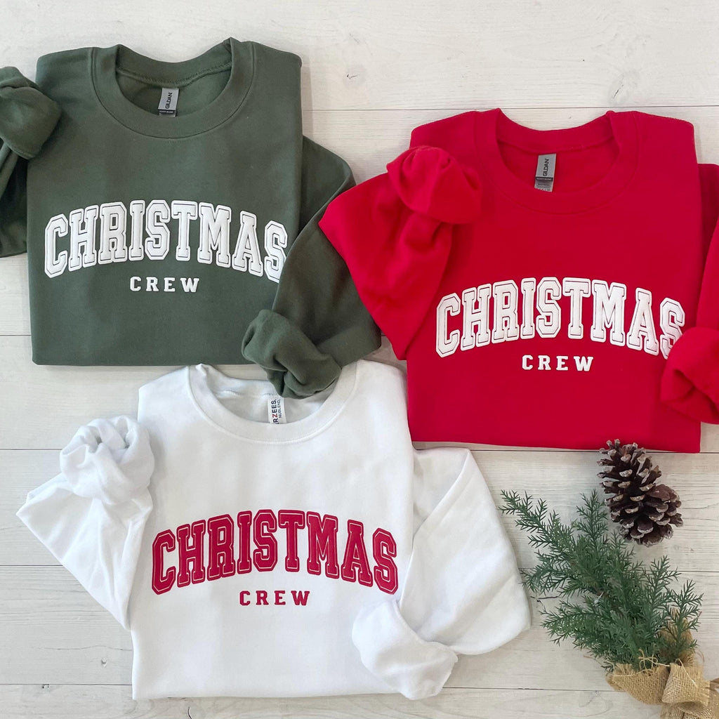 Red, white, and green Christmas crewneck sweatshirts with varsity-style “CHRISTMAS CREW” lettering