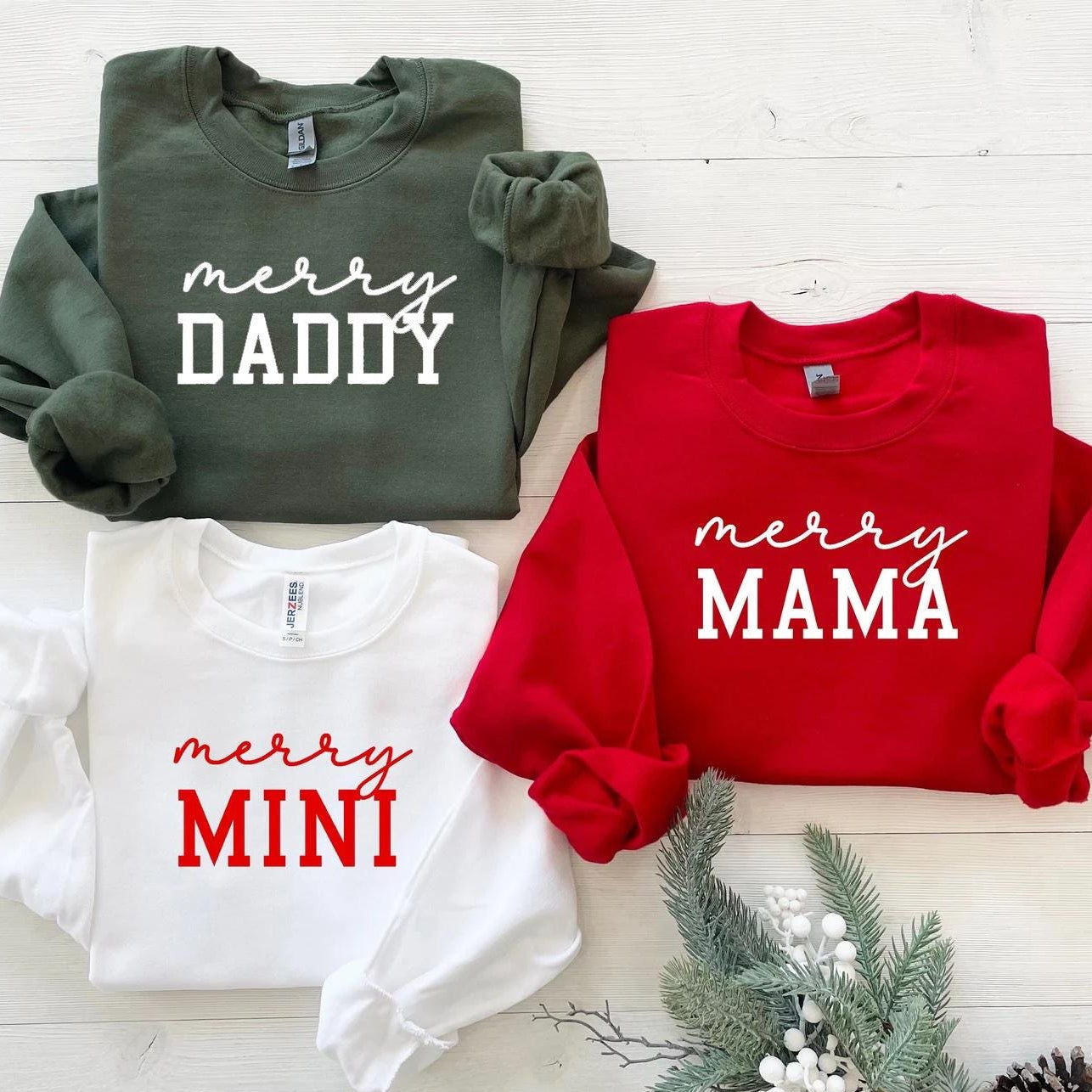Matching Christmas sweatshirts in red, white, and green with text “Merry Daddy”, “Merry Mama”, and “Merry Mini”